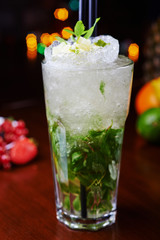 bright mojito cocktail on a table in the restaurant with the decor of ice and apple slices with bright backgrounds of beautiful disco lights. soft focus