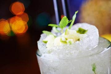 bright mojito cocktail on a table in the restaurant with the decor of ice and apple slices with bright backgrounds of beautiful disco lights. soft focus