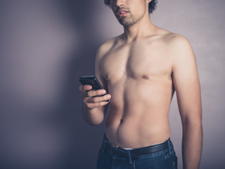 Fototapeta premium Young shirtless man with smartphone