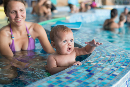 Young family with baby having fun in the swimming pool.