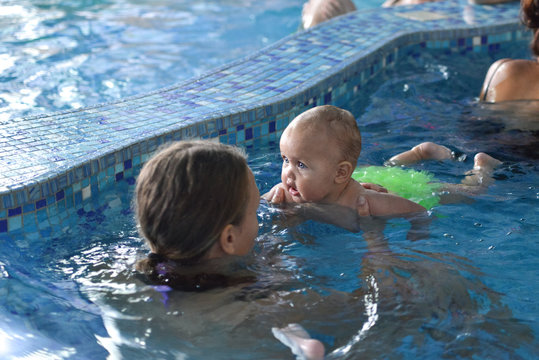 Young family with baby having fun in the swimming pool.