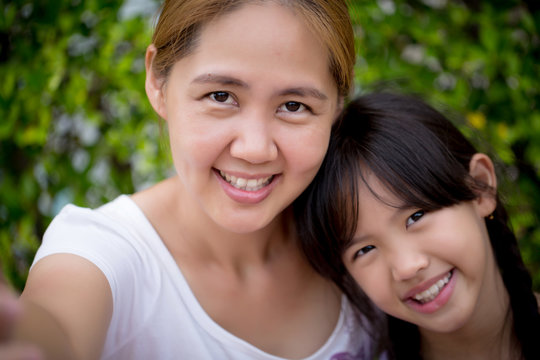 Asian mother and daughter taking selfie photograph together