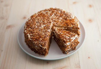 Homemade carrot and walnut cake with cut piece on a wooden table 