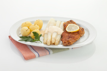 Wiener Schnitzel mit Sauce auf Spargel und Kartoffeln in der Pla
