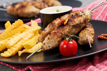 Barbecued kofta - kebeb with fries and vegetables on a plate.