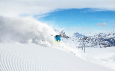 Naklejka na ściany i meble Skier skiing downhill in high mountains