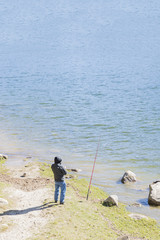 fisherman fishing on blue lake
