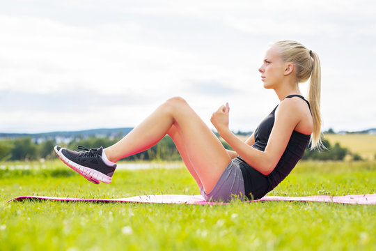 Young Woman Doing Sit Ups In The Park