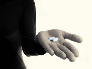 Black and white toned photo, open palm with blue pills