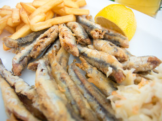 fried anchovy on a plate with fries