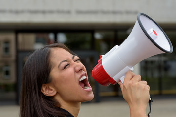 Angry young woman yelling over a megaphone