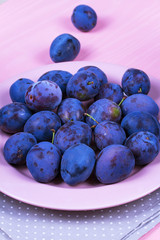 Fresh plums on pink plate