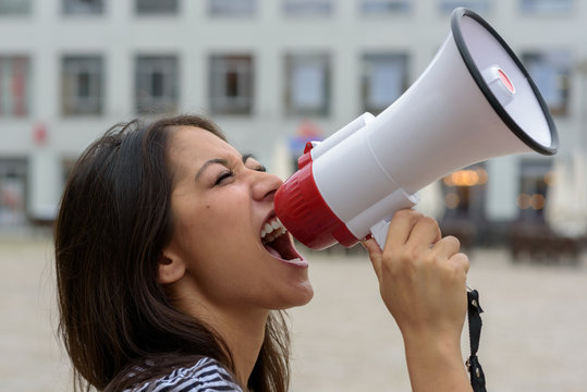 Woman yelling into a bullhorn on an urban street
