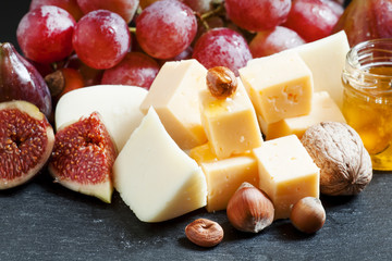 Сheese, figs, nuts and grapes on the old wooden background, sti