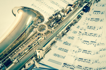 Part of saxophone lying on the notes. vintage style
