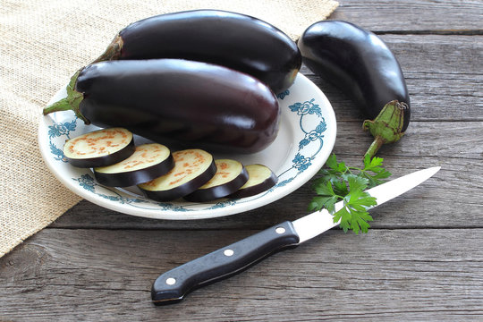 Sliced eggplant on plate on wood background