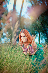 Romantic red-haired young woman in green long dress Walking