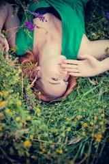 pensive dreamy attractive young red-haired woman with flowers