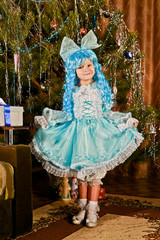The little girl in a New Year carnival costume at the Christmas tree