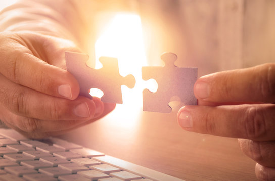 Closeup of man's hands holding puzzle pieces. Image can be used for background, website banner, promotional materials, poster, presentation templates, advertising and printed materials.