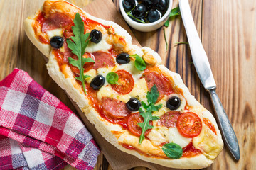 Homemade pizza with salami, black olives and fresh arugula