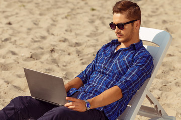 Handsome freelancer lying on the beach 