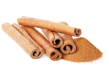 Closeup of cinnamon sticks and powder of ground cinnamon on white background