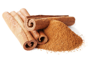 Closeup of cinnamon sticks and powder of ground cinnamon on white background