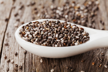 Chia seeds in white spoon on wooden table