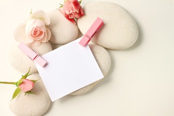 Empty note paper pink pins and delicate roses,white spa stones, feminine creamy tones decoration, blank space, soft focus