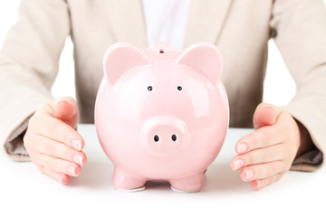 Pink piggy bank protected by hands