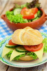 Cheese roll with lettuce, tomato and cucumber and bowl of green salad
