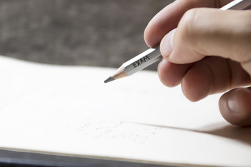 Student writing a test, an inscription on pencil "exam"