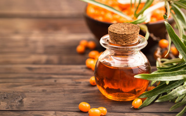 Sea buckthorn oil at right side of wooden background