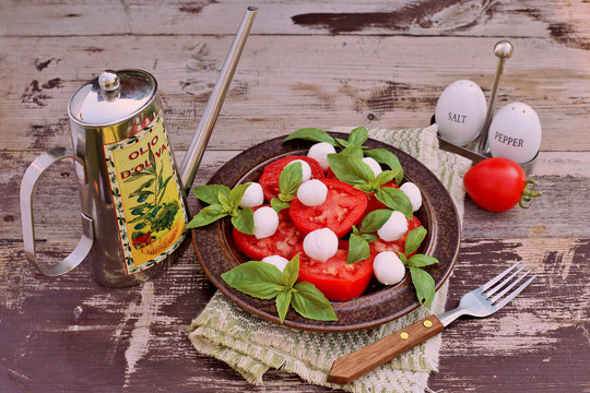 Mozzarella, tomatoes, basil , olive oil on wooden table