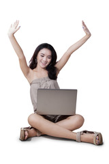 Cheerful girl using laptop and raise hands