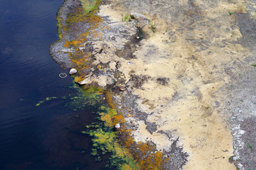 River with dirty polluted water and colorful sand during drought