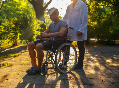 Man in wheelchair and his doctor in a park.