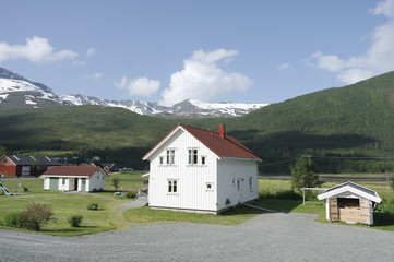 Fototapeta na wymiar белый норвежский дом на фоне зеленых холмов 