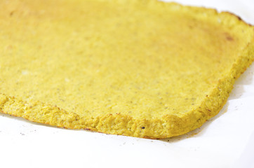 Cauliflower pizza crust. A healthy low carb, gluten free, vegan, vegetarian snack with grated cauli flower baked in the oven isolated on white background on parchment baking paper
