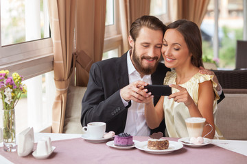 Cute boyfriend and girlfriend are using telephone in cafe