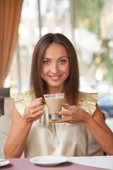 Beautiful young businesswoman is enjoying hot drink