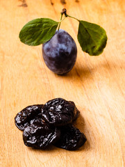 dried plums and fresh prune fruit on wooden table