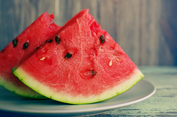 Fresh juicy slices of a watermelon on a plate on a wooden background.