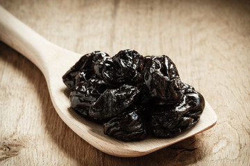 dried plums prunes on wooden spoon