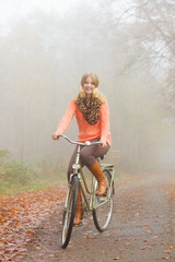 Fototapeta premium Happy active woman riding bike in autumn park.