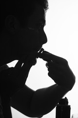 Silhouette man shaving using razor with cream foam