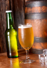 bicchiere di birra fredda con la bottiglia e la botte  sullo sfondo