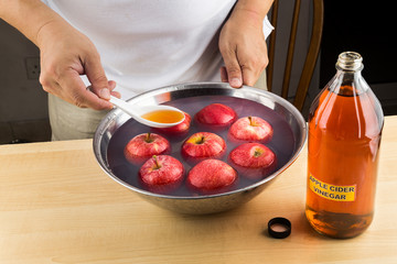 Hand pouring spoonful of Apple Cider Vinegar to soak and remove pesticides residue on fruits