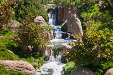 Naklejka na ściany i meble Small waterfall in the park at summer time. 